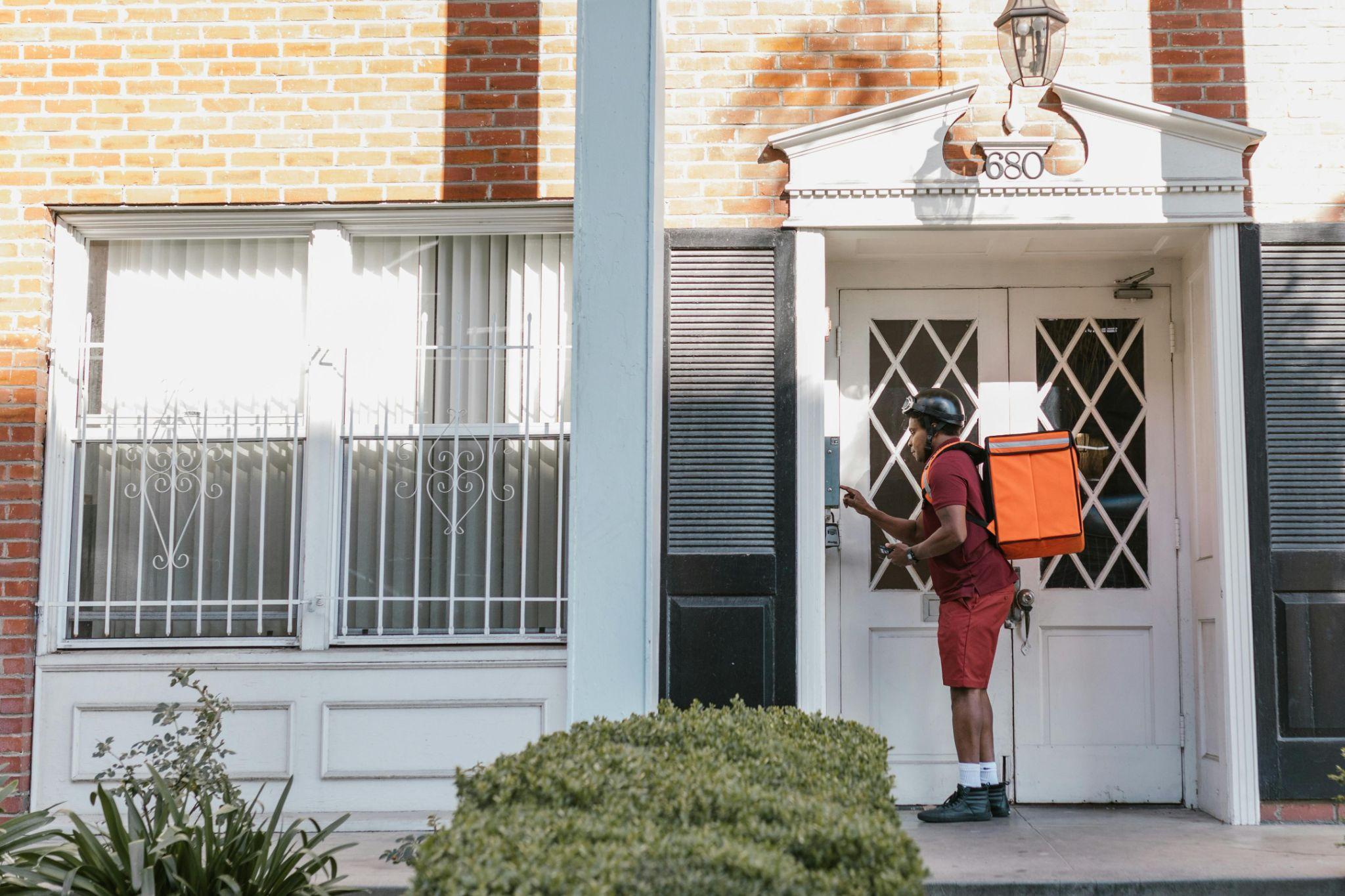 A delivery man using an intercom system outside a building.