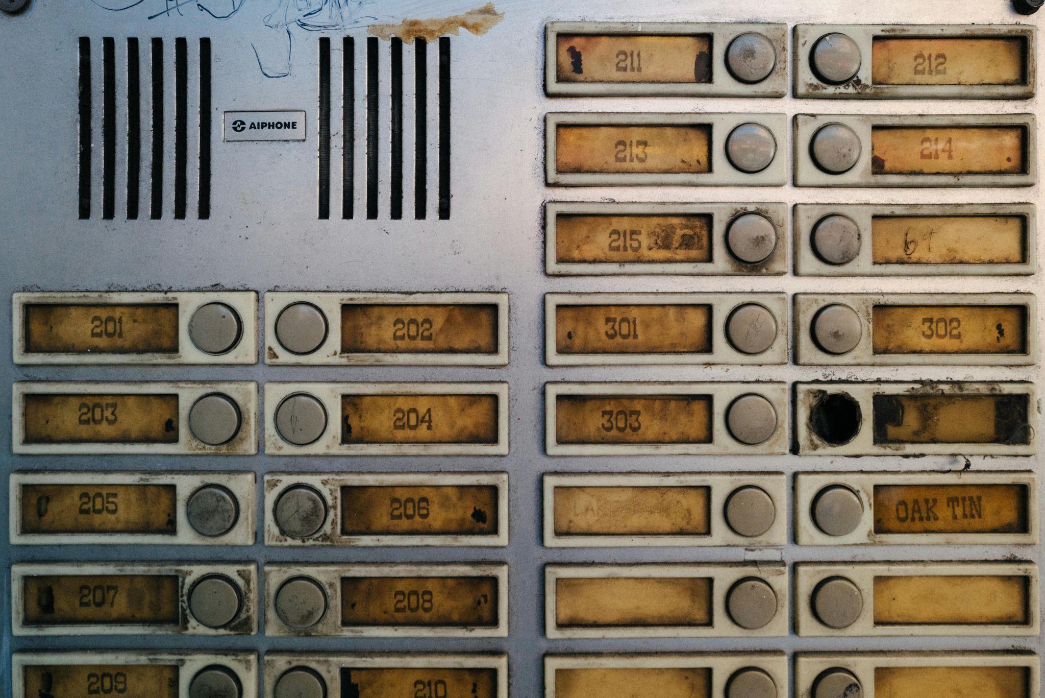 A person using an outdated intercom system at a building entrance.
